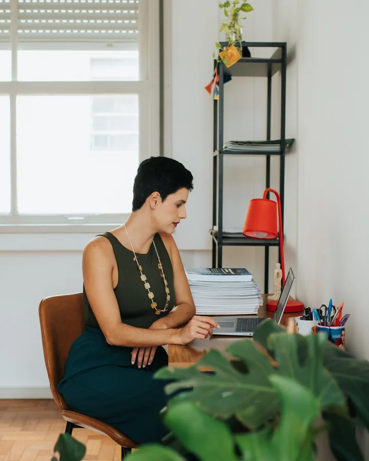 Karine em teleconsulta, no computador, à mesa do consultório